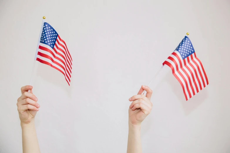 two hands holding american flags against a white background, by Carey Morris, pexels, 🚿🗝📝