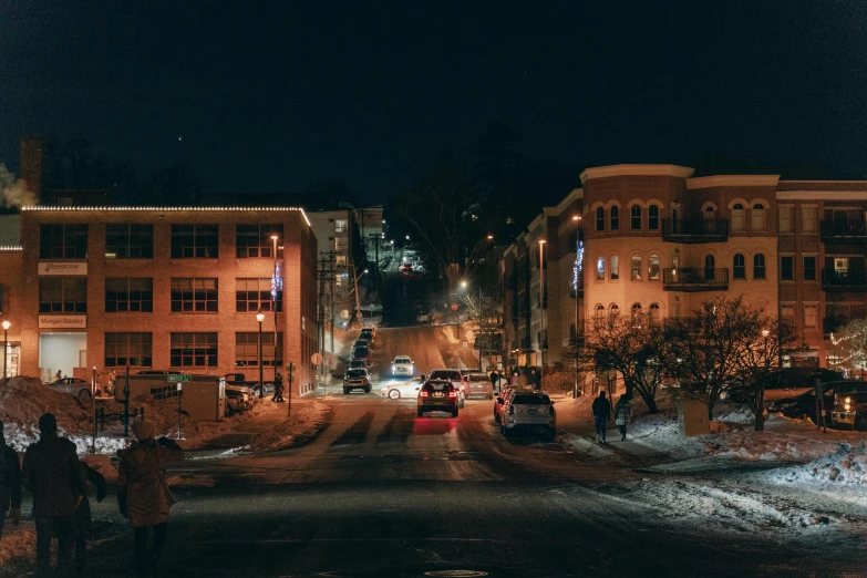 a street filled with lots of snow next to tall buildings, by Meredith Dillman, unsplash contest winner, taverns nighttime lifestyle, beautiful small town, cornell, college