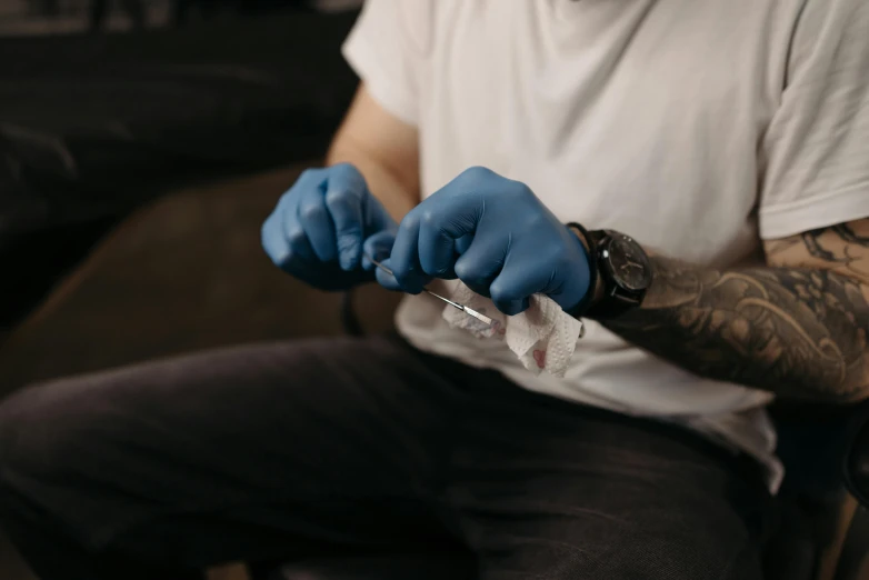 a man in a white shirt and blue gloves, a tattoo, trending on pexels, syringe, thumbnail, flattened, detailed acrylic