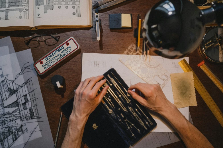 a person sitting at a desk working on a laptop, a drawing, by Lee Loughridge, pexels contest winner, gunsmithing, knolling, caligraphy, metalwork