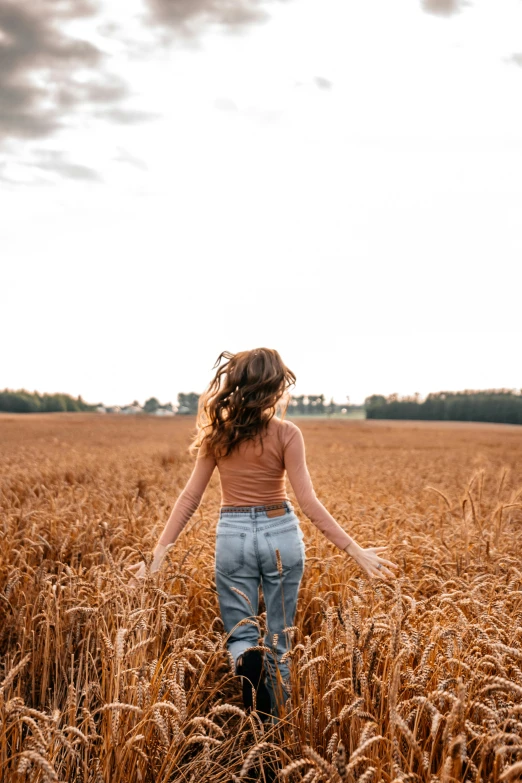 a woman is walking through a wheat field, trending on pexels, happening, wavy hair spread out, 33mm photo, wide full body, college