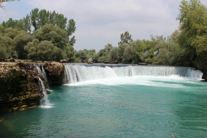 a waterfall in the middle of a river surrounded by trees, hurufiyya, split near the left, 2019 trending photo, ripple, al - qadim