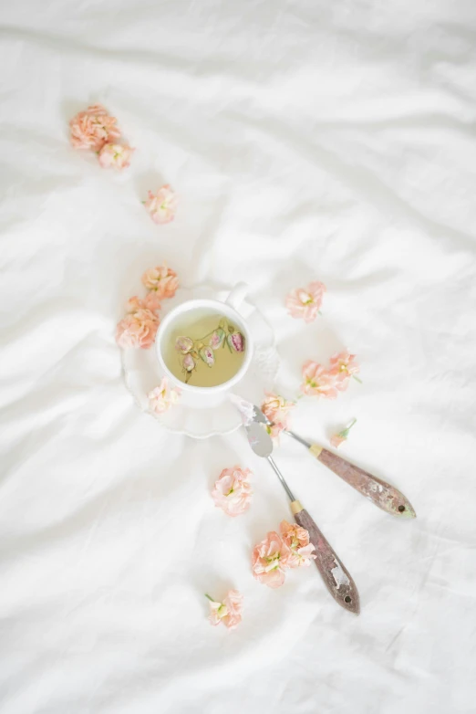 a couple of spoons sitting on top of a bed, by Grace Polit, trending on unsplash, romanticism, pastel flower petals flying, green tea, milk, in a white boho style studio