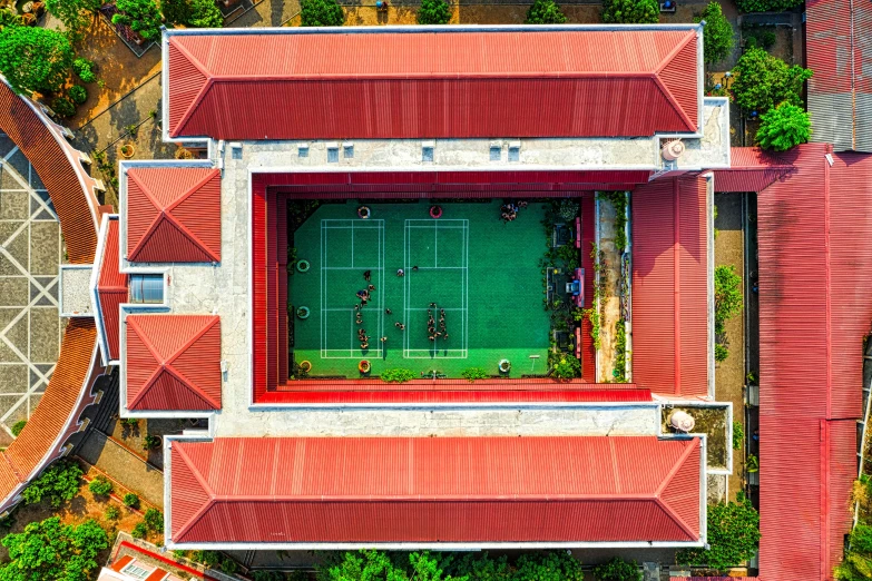 an aerial view of a tennis court surrounded by trees, bengal school of art, red building, star roof, upside - down building, flat lay