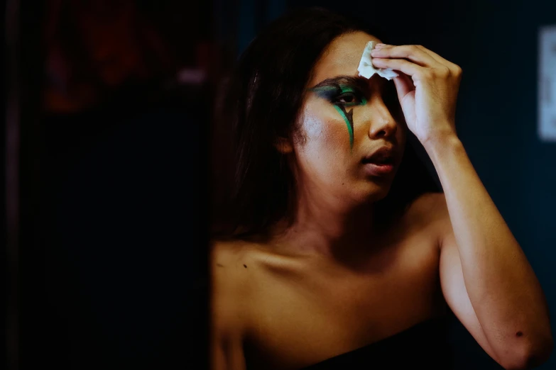 a woman with green paint on her face, an album cover, inspired by Elsa Bleda, trending on pexels, weeping tears of black oil, looking in mirror, an asian woman, beautiful crying! android woman