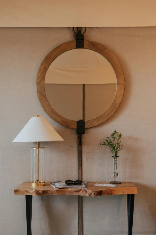 a wooden table topped with a lamp next to a mirror, inspired by Constantin Hansen, unsplash, renaissance, architectural digest, circular face, washington dc, seasonal