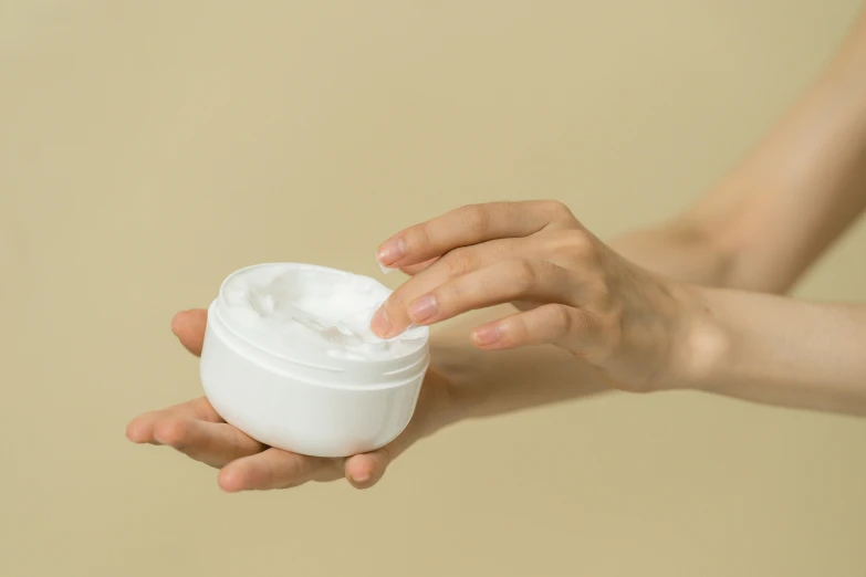 a woman holding a jar of cream in her hand, trending on pexels, white pearlescent, curved, product view, round-cropped