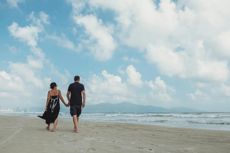 a man and woman walking on a beach holding hands, by Arabella Rankin, pexels contest winner, vietnam, background image, thumbnail, blue sky