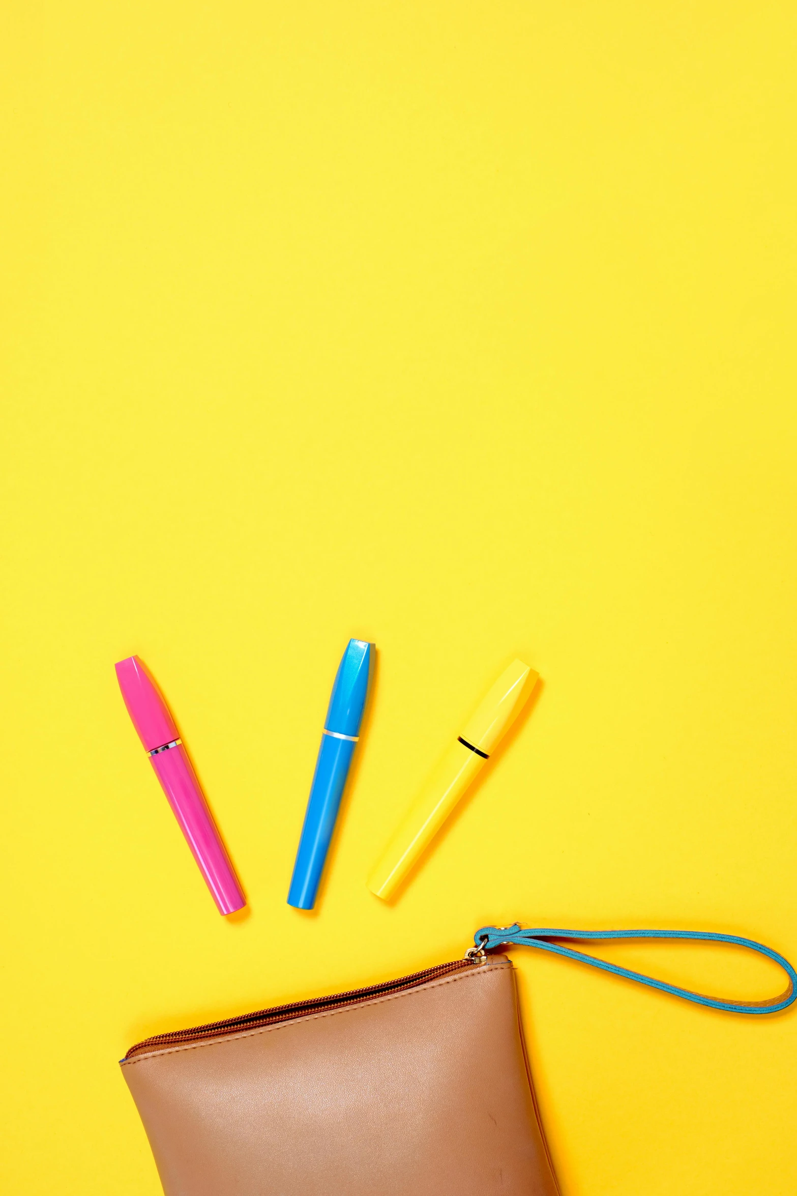 a brown purse sitting on top of a yellow surface, colored marker, pink and blue colour, lipstick, background image