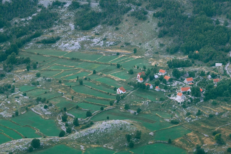 a group of houses sitting on top of a lush green hillside, by Petr Brandl, hurufiyya, view from helicopter, split near the left, csók istván, limestone