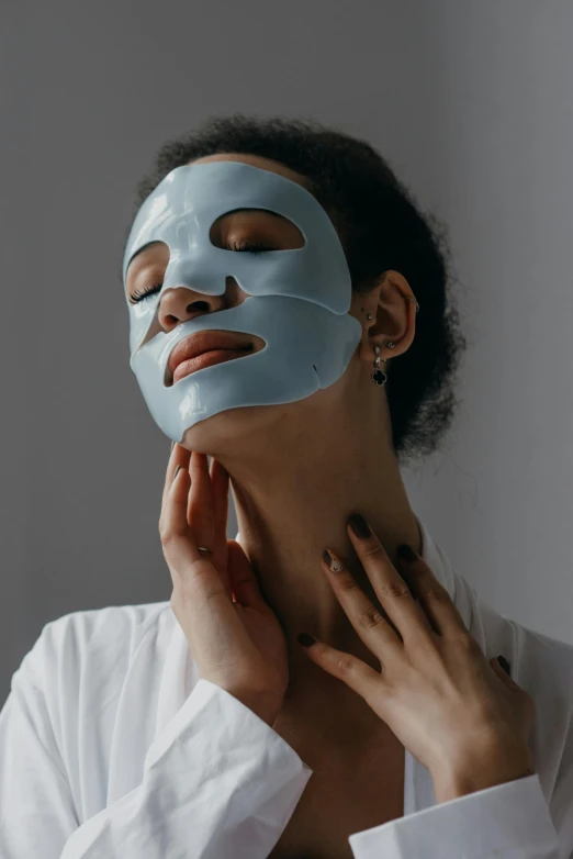 a woman with a blue mask on her face, trending on pexels, on grey background, silicone skin, woman holding another woman, glomy