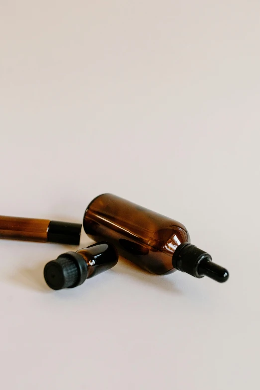 a couple of bottles sitting on top of a table, product image, amber, spray, on a pale background