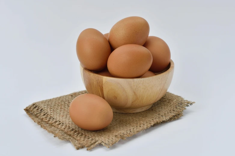 a wooden bowl filled with eggs on top of a table, trending on pexels, beige, detailed product image, frontal shot, angled