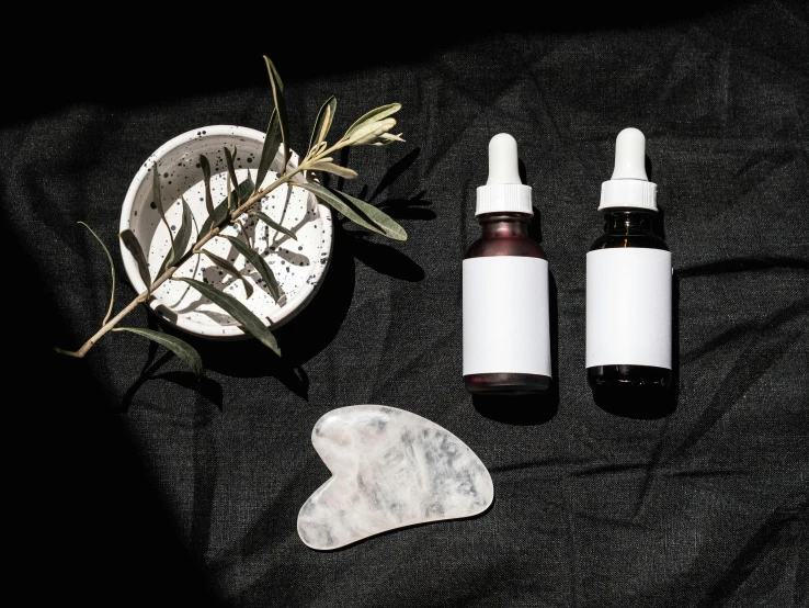 a couple of bottles sitting on top of a table, by Julia Pishtar, trending on pexels, small vials and pouches on belt, black oil bath, eucalyptus, white moon and black background