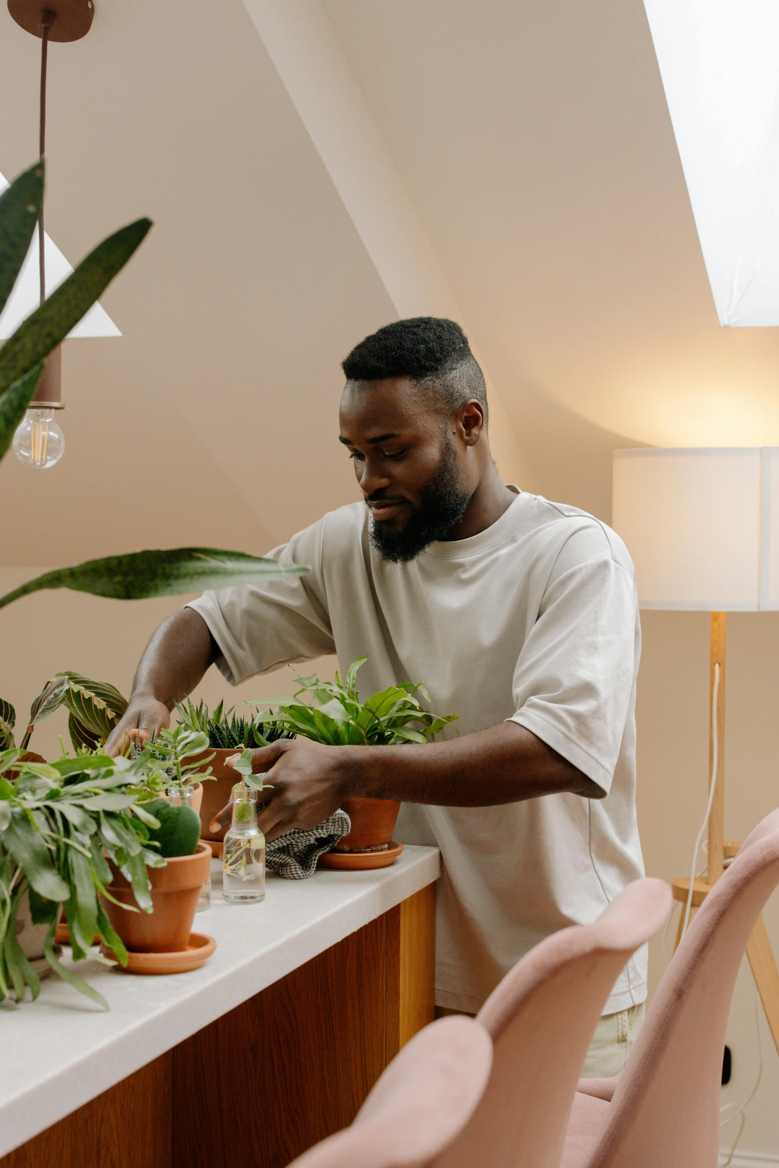 a man standing in front of a table filled with potted plants, black man, tending on pinterest, concentrated, pouring