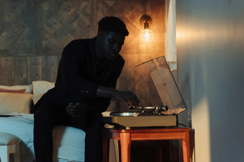 a man sitting on a bed using a record player, trending on pexels, ( ( dark skin ) ), elegant scene, standing in a dimly lit room, obunga