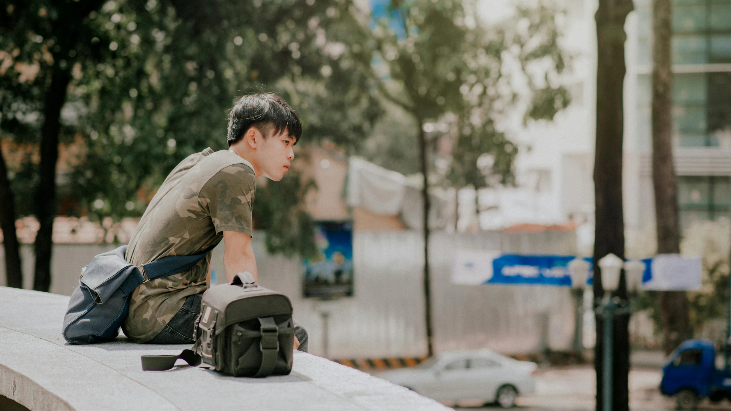 a man sitting on a ledge with a backpack, by Wen Zhenheng, pexels contest winner, vietnam soldier with skateboard, avatar image, looking her shoulder, thin young male