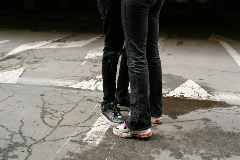 a couple of people standing on top of a skateboard, trending on pexels, black denim pants, nike air max, close-up photo, intersection