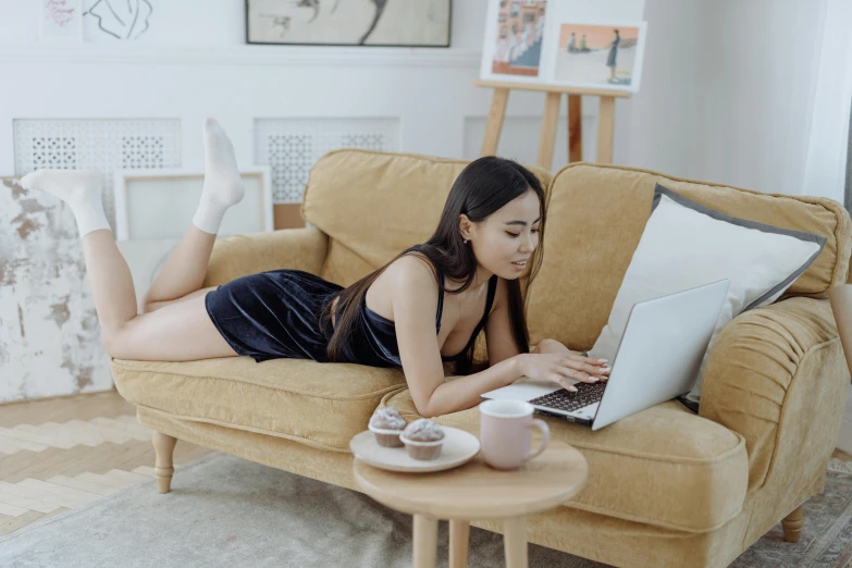 a woman laying on a couch using a laptop, a cartoon, trending on pexels, exposed thighs, asian girl with long hair, full length shot, candid photograph