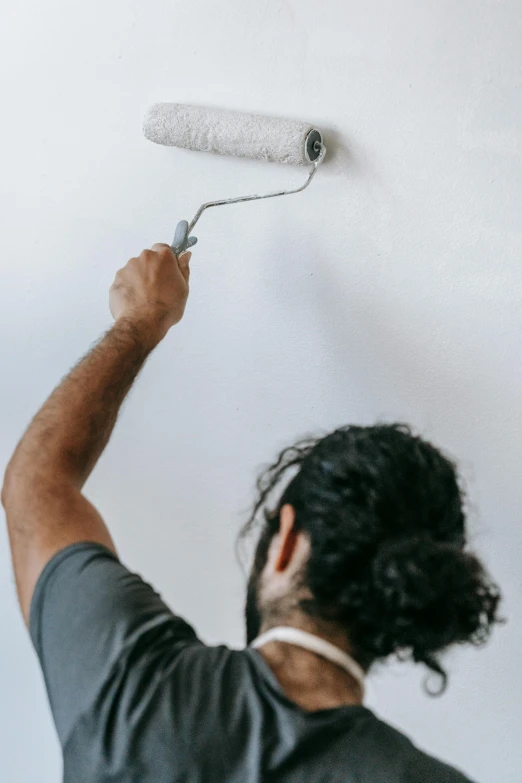 a man painting a wall with a paint roller, a minimalist painting, pexels contest winner, white ceiling, plain background, ox, a handsome