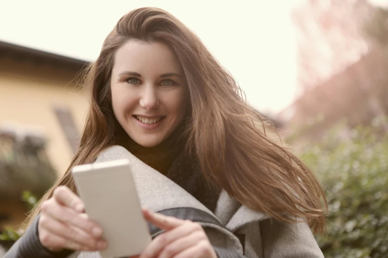 a woman holding a tablet computer in her hands, pexels contest winner, happening, girl with brown hair, portrait of white teenage girl, uploaded, warm coloured