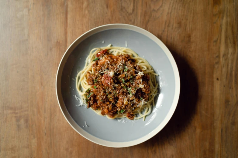 a plate of spaghetti on a wooden table, by Carey Morris, pexels contest winner, ground meat, dwell, grey, tall