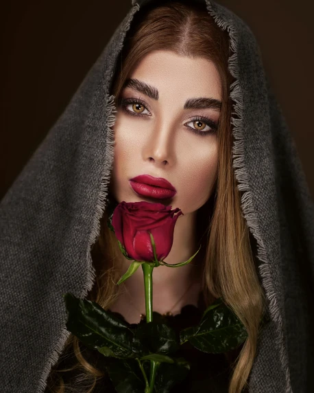 a woman holding a rose in front of her face, an album cover, inspired by Hedi Xandt, unsplash contest winner, wearing cloak and hood, non binary model, 5 0 0 px models, beautiful arab woman