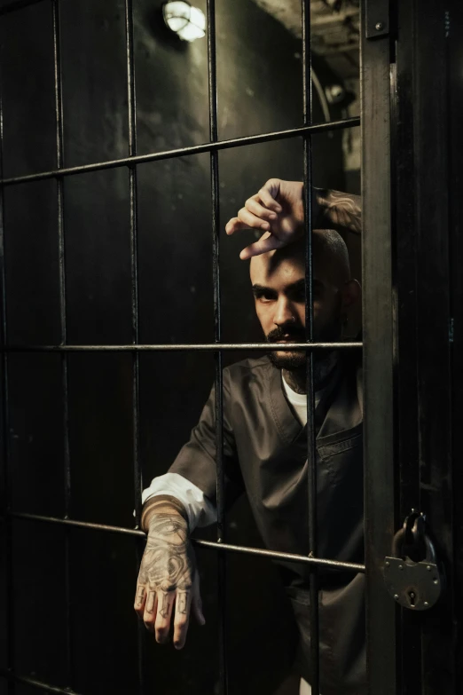 a man in a jail cell with his hands on the bars, a portrait, inspired by James Bolivar Manson, trending on pexels, renaissance, zayn malik, bearded man, looking serious, photo from a promo shoot