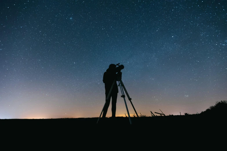 a man standing on top of a hill next to a camera, pexels contest winner, visual art, star charts, space telescope, profile picture, low-light photograph