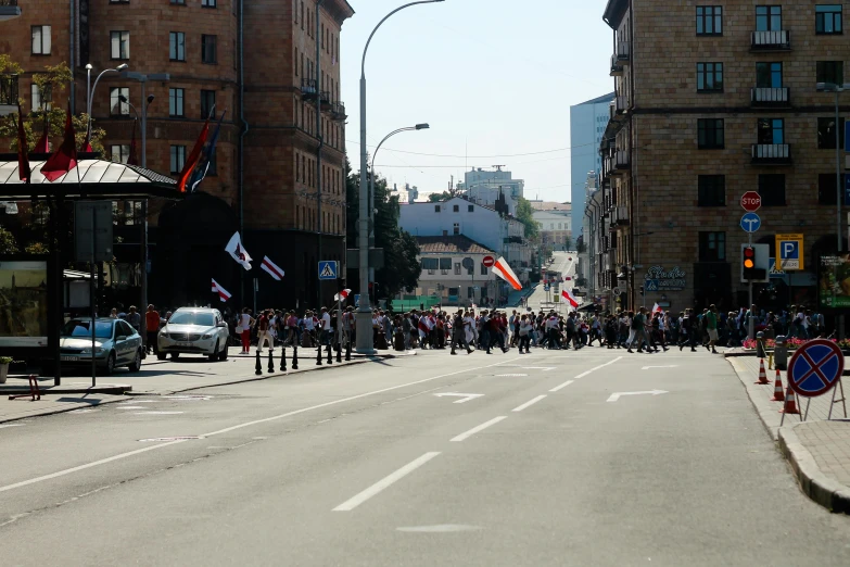 a crowd of people walking down a street next to tall buildings, reddit, socialist realism, president of belorussia, low quality photo, protest, on a sunny day