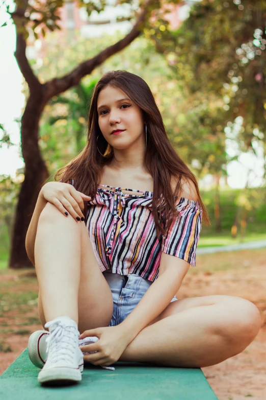 a woman sitting on top of a green bench, a picture, by Luis Miranda, instagram, renaissance, croptop and shorts, portrait of a young teenage girl, striped, sitting under a tree