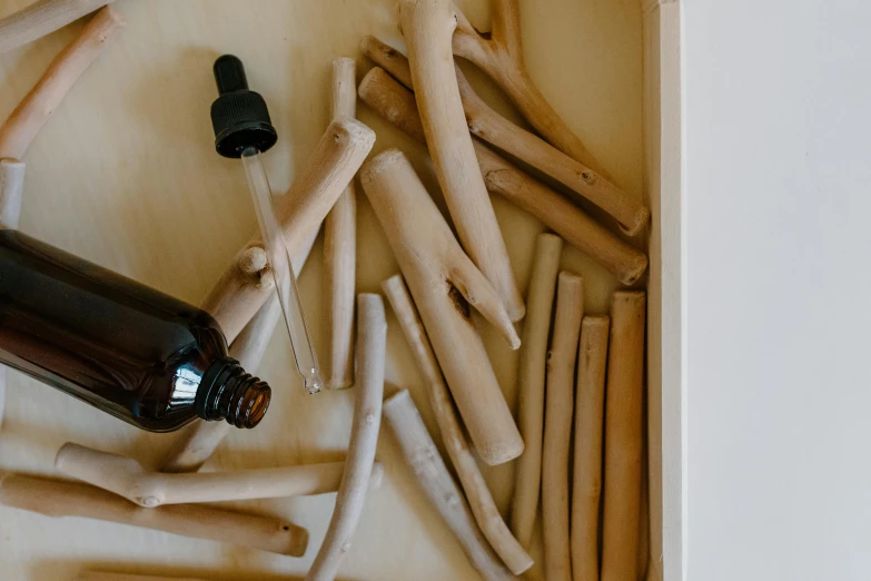 a brown bottle sitting on top of a wooden table, by Emma Andijewska, trending on pexels, process art, they sit next to a pile of bones, healing tubes, wooden cabinet, skincare