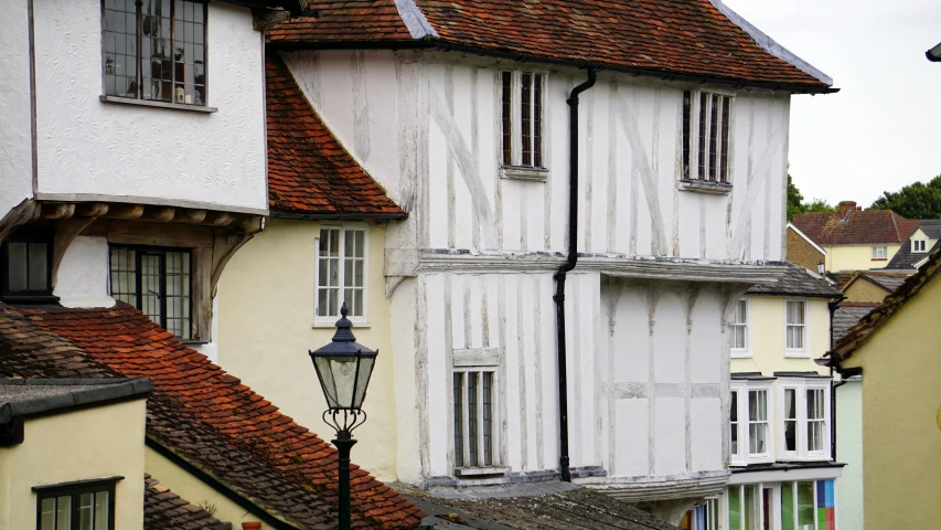 a couple of buildings that are next to each other, inspired by William Nicholson, pexels contest winner, arts and crafts movement, white wall, medieval, houses on stilts, filling the frame