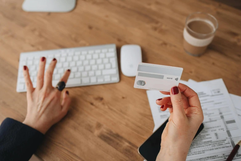 a close up of a person holding a credit card, by Adam Marczyński, pexels contest winner, private press, square, sitting on a desk, woman holding another woman, white