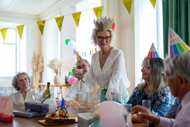 a group of people sitting around a table at a birthday party, pexels contest winner, happening, wearing a light grey crown, an ahoge stands up on her head, middle - age, delightful surroundings