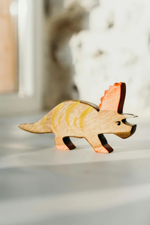 a close up of a toy dinosaur on a table, inspired by Adam Rex, unsplash, wooden jewerly, triceratops, official product photo, angled view