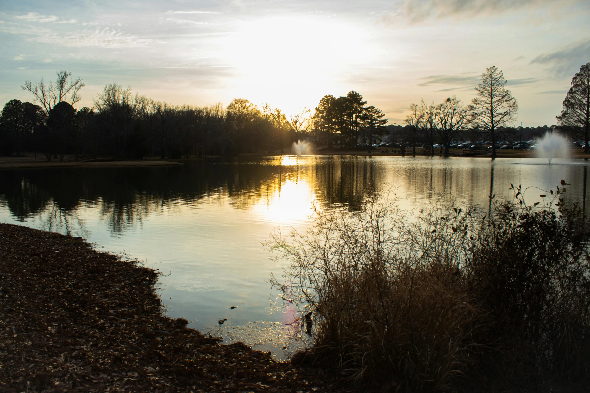 a lake filled with lots of water next to a forest, by Carey Morris, unsplash, visual art, winter sun, bentonville arkansas, 2000s photo, sundown