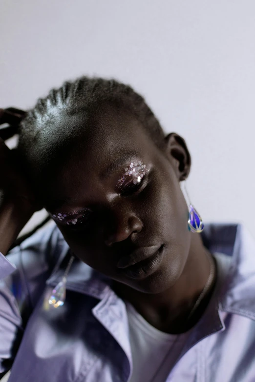 a close up of a person holding a cell phone, an album cover, by Nathalie Rattner, trending on unsplash, afrofuturism, huge earrings and queer make up, model posing, glittering light, adut akech