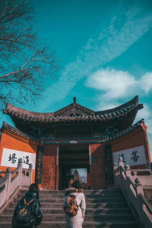 a woman standing in front of a building, inspired by Gu An, pexels contest winner, mingei, chinese temple, clear blue skies, huge gate, wuxia