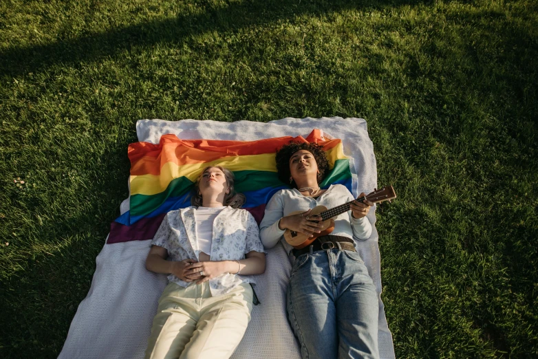 a couple of people laying on top of a grass covered field, an album cover, by Julia Pishtar, pexels, lgbt flag, musicians playing instruments, laying in bed, 🚿🗝📝