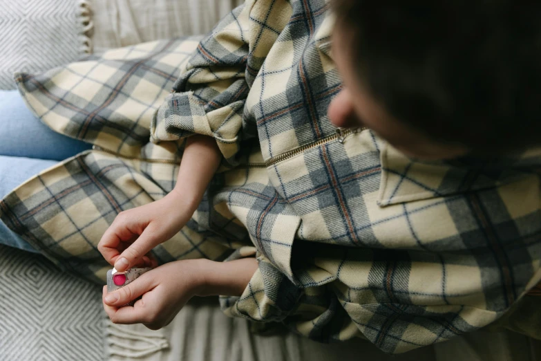 a woman sitting on top of a bed covered in a blanket, a child's drawing, trending on pexels, plaid shirt, holding hands, embedded with gemstones, candid photography