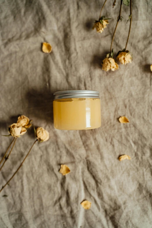 a jar of body butter surrounded by dried flowers, by Alice Mason, unsplash, raw egg yolks, thumbnail, juice, relaxed. gold background