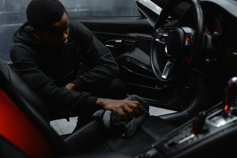 a man sitting in the driver's seat of a sports car, pexels contest winner, black skin, inspect in inventory image, black cloth, cleaned up