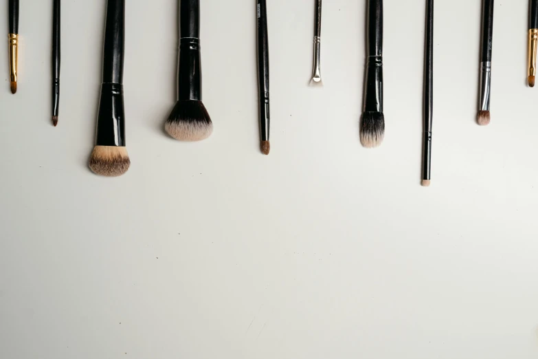 a bunch of makeup brushes hanging on a wall, by Gavin Hamilton, trending on unsplash, minimalism, fan favorite, white backdrop, miniature product photo, black eyeliner