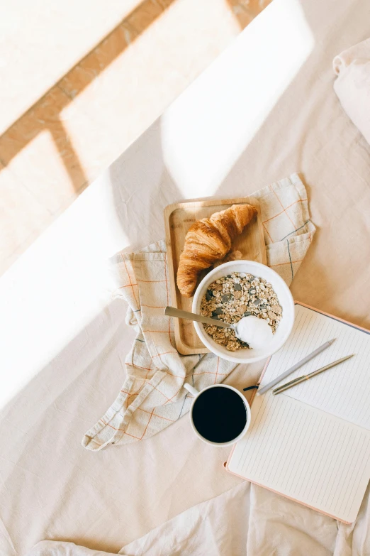 a laptop computer sitting on top of a bed next to a cup of coffee, a still life, trending on unsplash, cereal, sun rising, white tablecloth, black