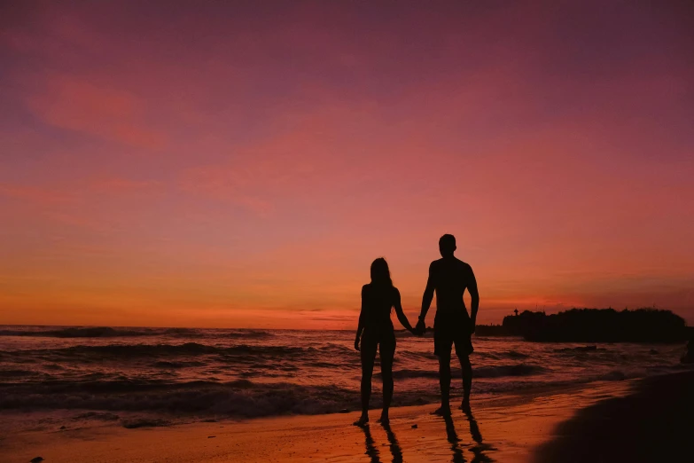 a couple holding hands on the beach at sunset, by Gwen Barnard, pexels contest winner, orange / pink sky, profile image, nighttime, standing on a beach in boracay