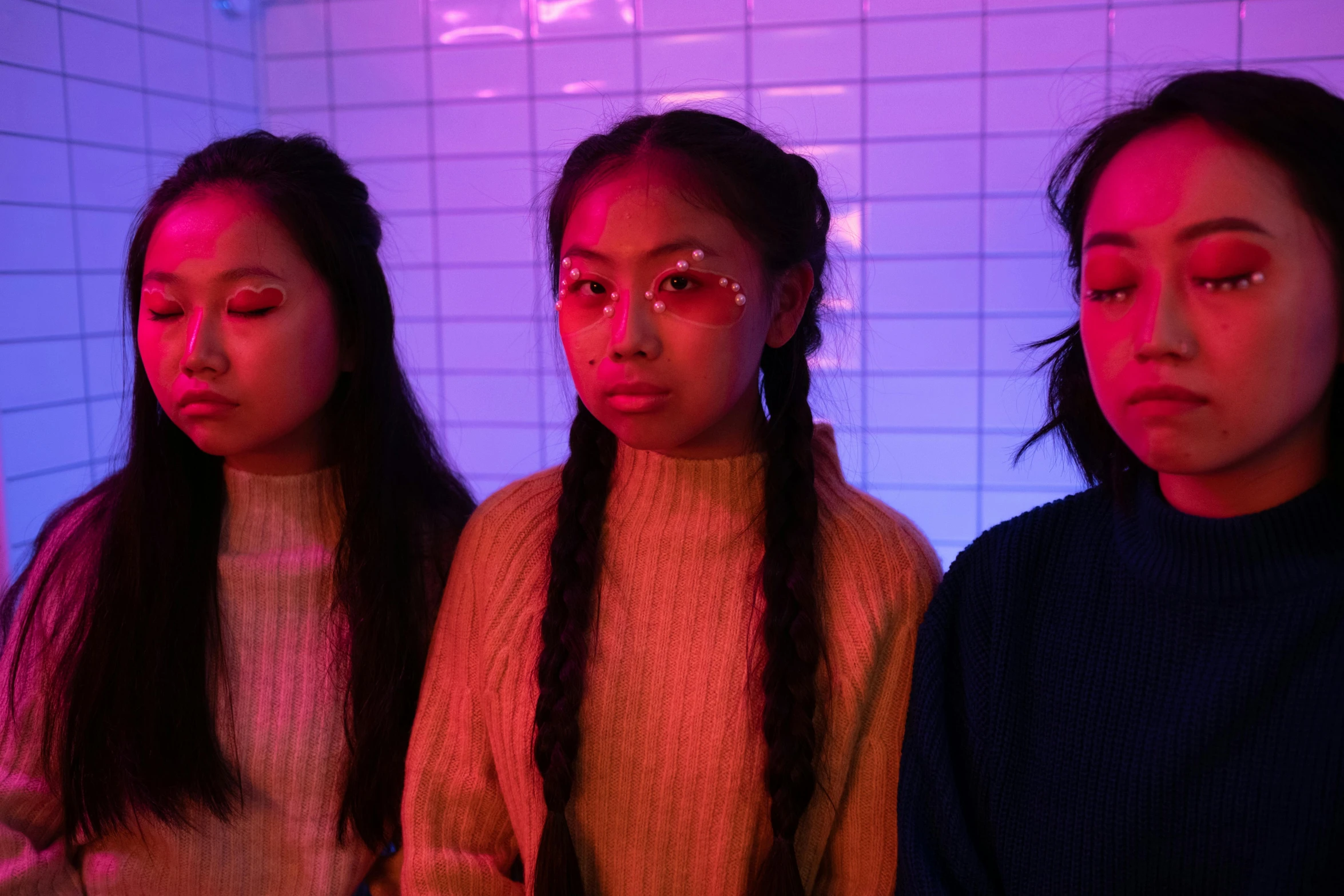 a group of young women standing next to each other, an album cover, trending on pexels, neon backlighting, three heads, asian descent, braids