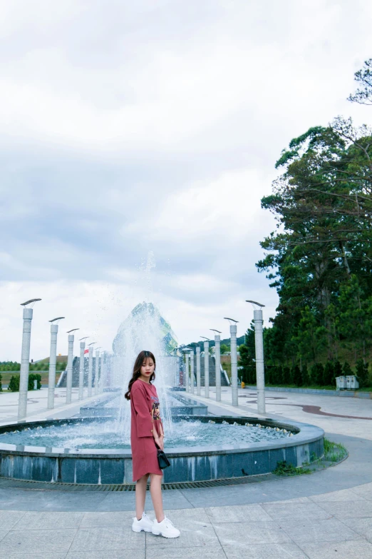 a woman in a red dress standing in front of a fountain, taiwan, bright sky, in karuizawa, high-quality photo