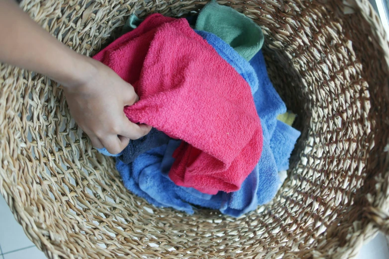 a person that is holding some towels in a basket, by Alice Mason, pexels, process art, brand colours are red and blue, dirty green clothes, thumbnail, playing