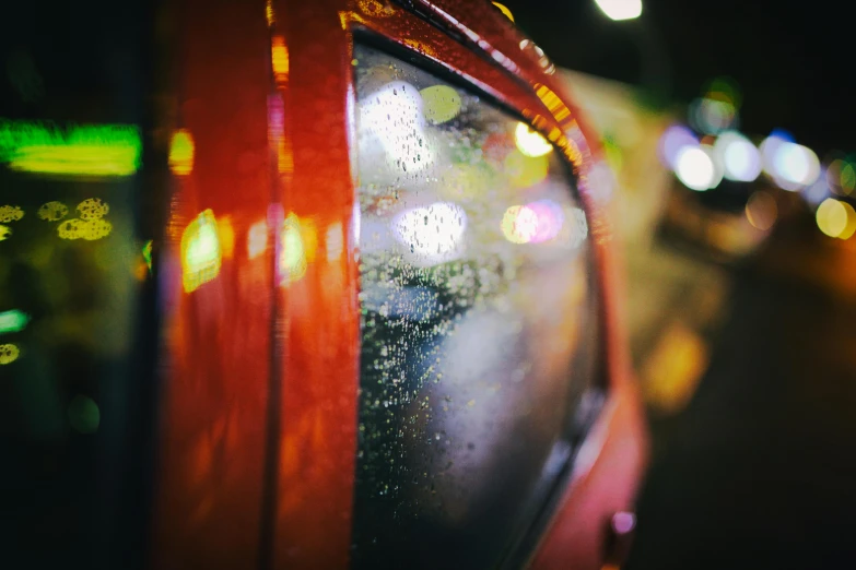 a red car on a city street at night, pexels contest winner, photorealism, water droplets on lens, hasselblad film bokeh, orange neon, grainy